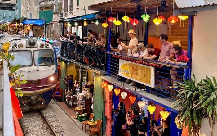Tourists watching train pass from Hanoi Train Street cafes